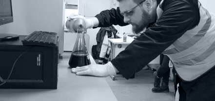 lab worker pours chemicals into a container during the creation of a new product